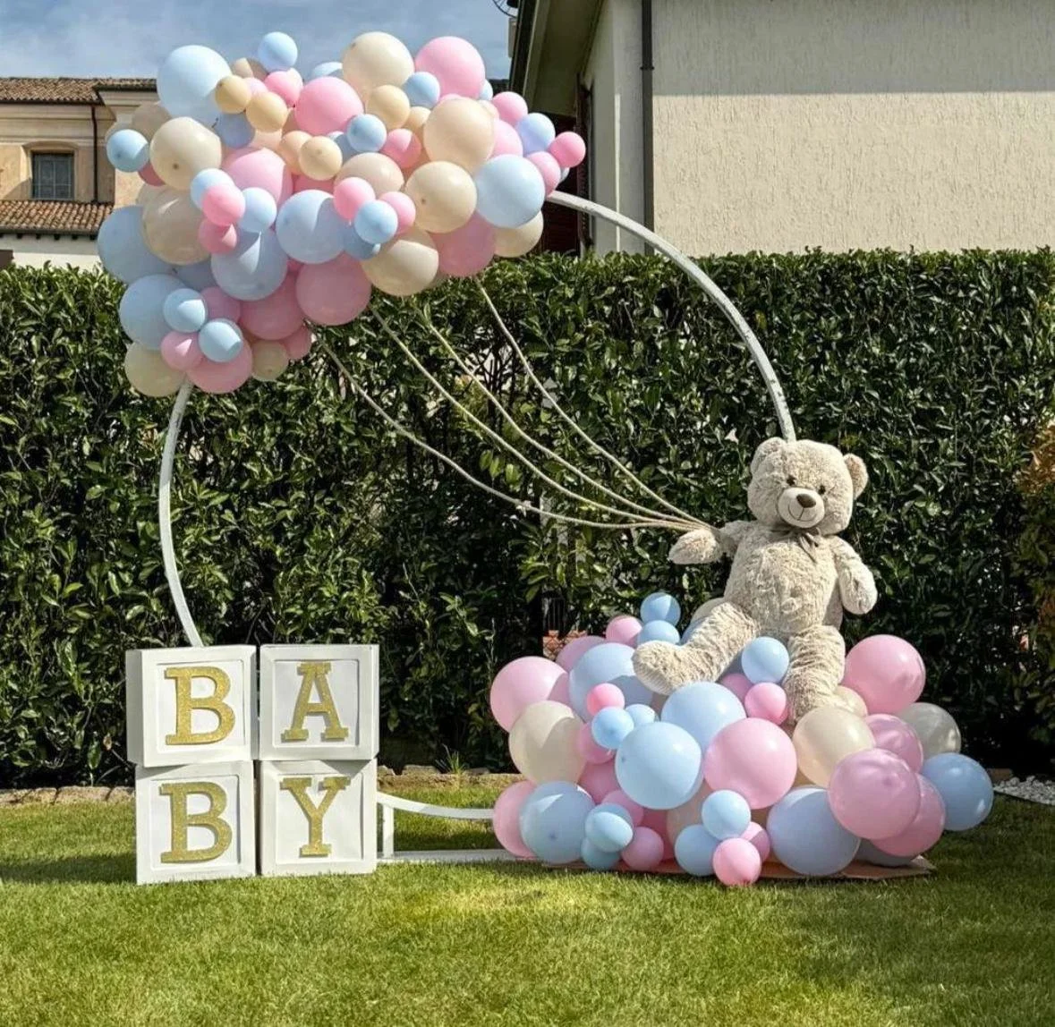 Decorazione per nascita con orsetto di peluche, palloncini rosa, azzurri e crema, e blocchi con la scritta "BABY".