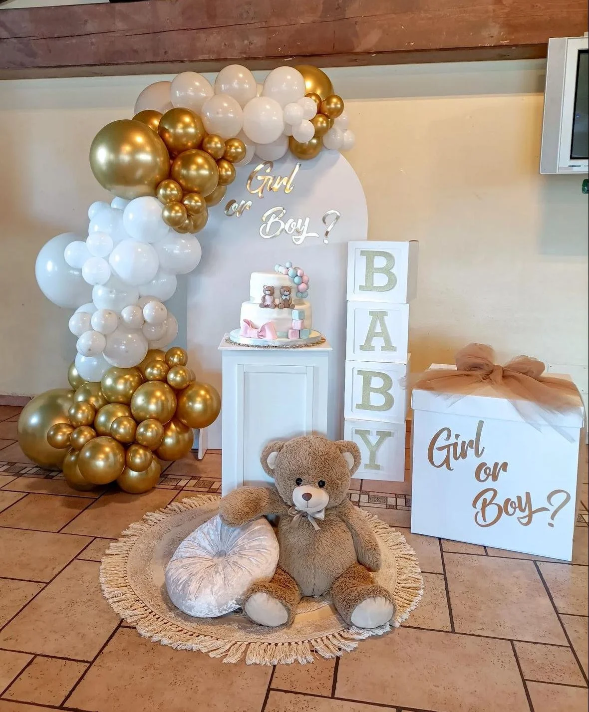 Decorazione per nascita con palloncini bianchi e dorati, teddy bear, torta con orsetti, scatole con lettere che formano la parola Baby, e box con scritto Girl or Boy?